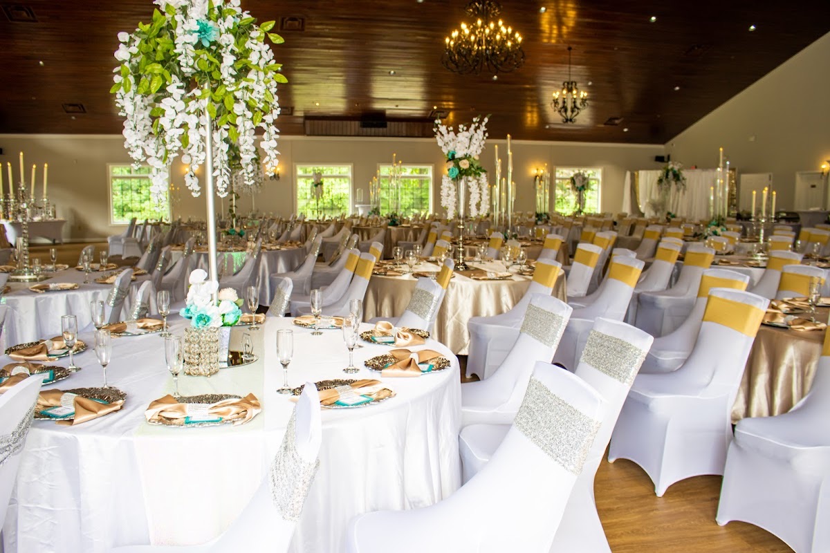 Elegant wedding reception set with white and gold tables beneath chandeliers at Merle Manders Conference Center in Stockbridge, GA